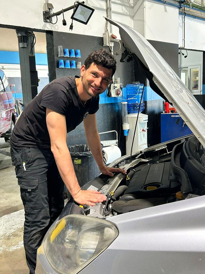 Smiling mechanic with the bonnet open